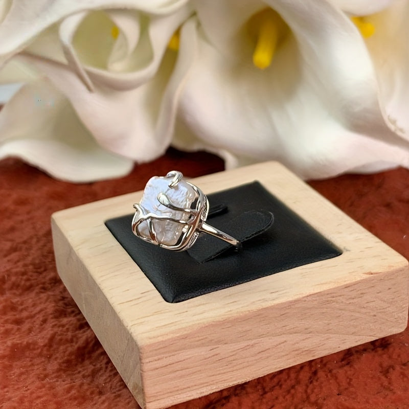 Elegant silver ring featuring a single glowing pearl and polished finish.