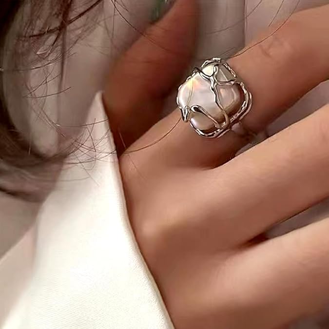 Elegant silver ring featuring a single glowing pearl and polished finish.